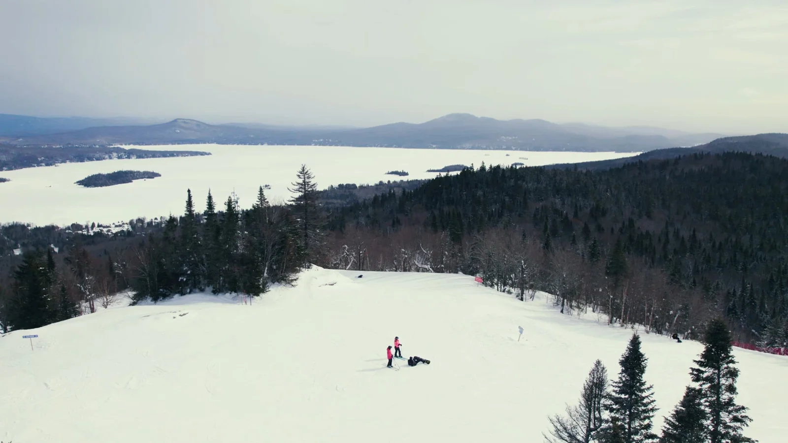 Deux personnes dans un paysage enneigé, devant un lac et les montagnes